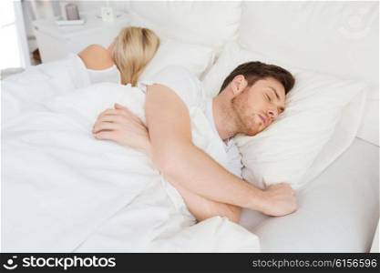 people, relationship difficulties, conflict and family concept - couple sleeping back to back in bed at home