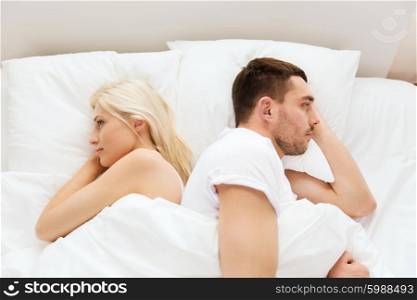 people, relationship difficulties, conflict and family concept - unhappy couple lying back to back in bed at home