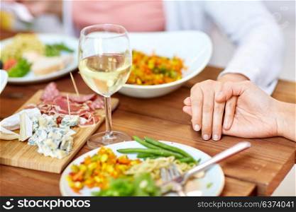 people, relationships and eating concept - hands of people sitting at table with food and praying before meal. hands of people at table praying before meal