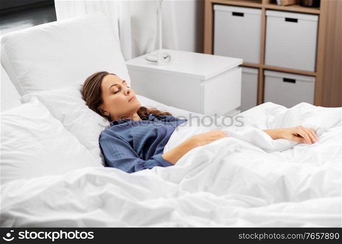 people, relax and comfort concept - young woman sleeping in bed at home. young woman sleeping in bed at home