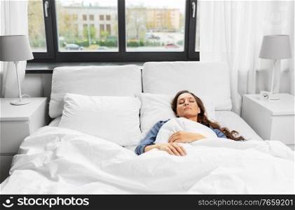 people, relax and comfort concept - young woman sleeping in bed at home. young woman sleeping in bed at home