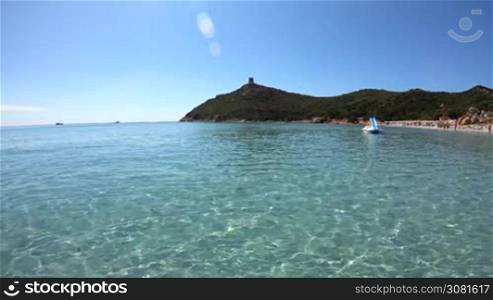People relaxing on holiday in Italy, families and tourists on summer vacations. Italian coast in Sardinia on Mediterranean Sea. Sandy beach in Porto Giunco, Villasimius, Sardegna, Italia