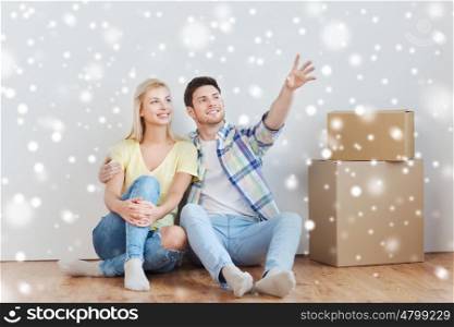 people, repair and real estate concept - smiling couple with boxes moving to new home and dreaming over snow