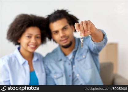 people, repair and real estate concept - smiling couple with key and cardboard boxes moving in or out of home. happy couple with key and boxes moving to new home