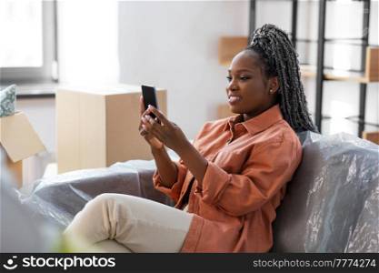 people, repair and real estate concept - woman with smartphone and boxes moving to new home. woman with smartphone and boxes moving to new home