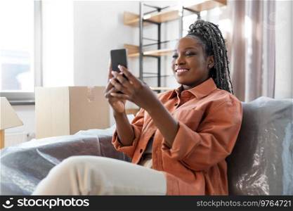 people, repair and real estate concept - woman with smartphone and boxes moving to new home. woman with smartphone and boxes moving to new home