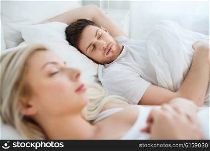 people, rest and relationships concept - happy couple sleeping in bed at home