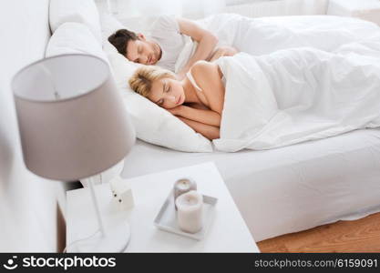 people, rest and relationships concept - happy couple sleeping in bed at home