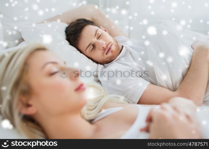 people, rest and relationships concept - happy couple sleeping in bed at home over snow