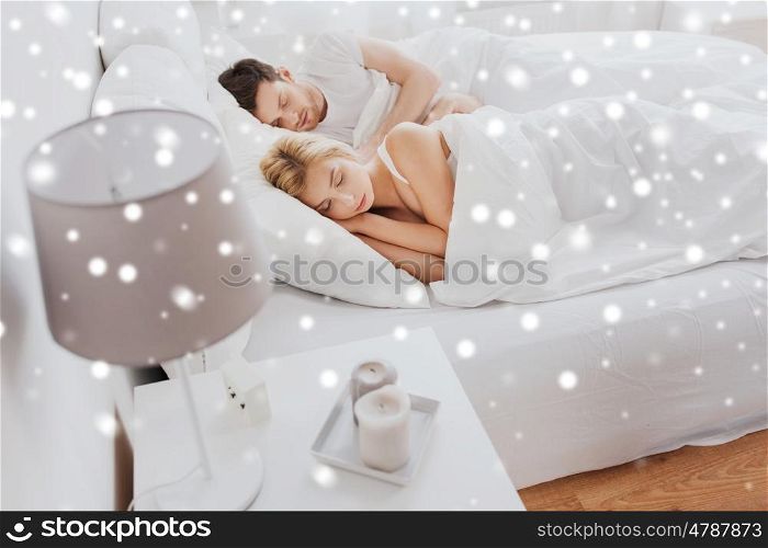 people, rest and relationships concept - happy couple sleeping in bed at home over snow