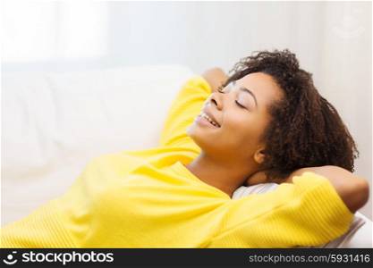 people, rest, comfort and leisure concept - happy african young woman relaxing or dreaming at home
