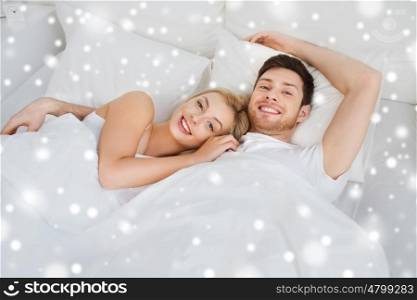 people, rest, love, relationships and happiness concept - happy smiling couple lying in bed at home over snow