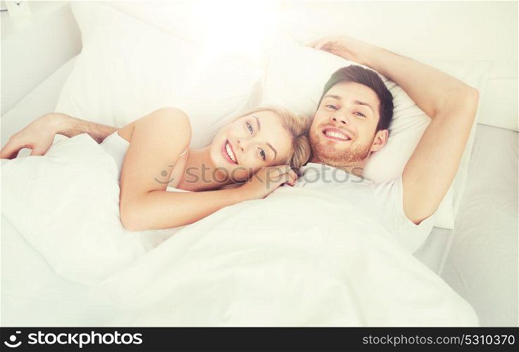 people, rest, love, relationships and happiness concept - happy smiling couple lying in bed at home. happy couple lying in bed at home