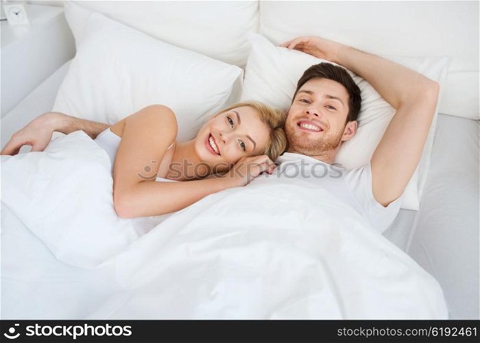 people, rest, love, relationships and happiness concept - happy smiling couple lying in bed at home