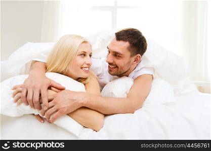 people, rest, relationships and happiness concept - happy couple in bed at home