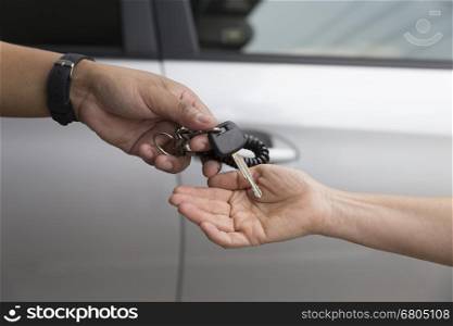people's hand give and get car key with silver car background