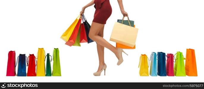 people, sale and consumerism concept - close up of woman in red short skirt and high heeled shoes with shopping bags
