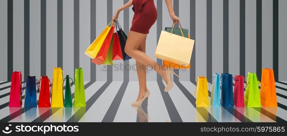 people, sale and consumerism concept - close up of woman in red short skirt and high heeled shoes with shopping bags over gray striped 3d background