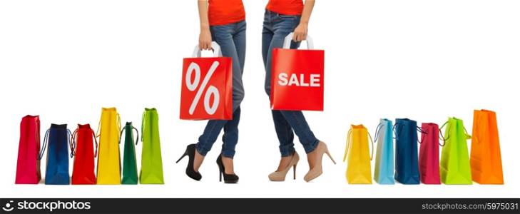people, sale and discount concept - close up of women with percentage sign on red shopping bag