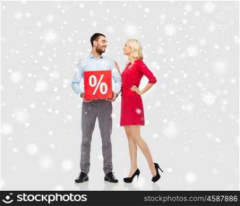 people, sale, christmas, winter shopping and holidays concept - happy couple with red percentage sign over snow background