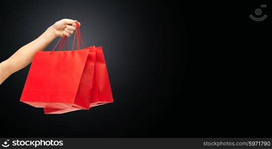 people, sale, consumerism, advertisement and black friday concept - close up of hand holding red blank shopping bags