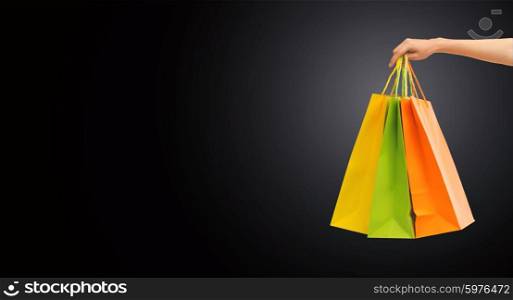 people, sale, consumerism, advertisement and black friday concept - close up of hand holding shopping bags