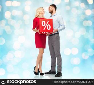 people, sale, discount and holidays concept - happy couple with red percentage sign over blue holidays lights background