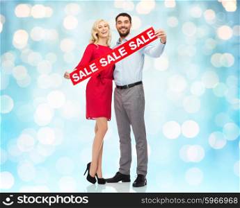 people, sale, discount and holidays concept - happy couple with red sale sign over blue lights background