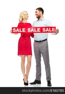 people, sale, discount and holidays concept - happy couple with red sale sign looking at each other