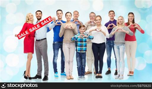 people, sale, discount and shopping concept - happy people with red sign showing heart shape