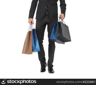 people, sale, fashion and consumerism concept - close up of man in suit with shopping bags