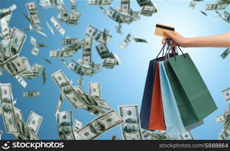 people, sale, finance and consumerism concept - close up of male hand holding shopping bags and bank or credit card over blue background and money rain