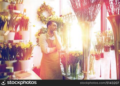 people, sale, retail, business and floristry concept - happy smiling florist man with cashbox standing at flower shop. florist man or seller at flower shop