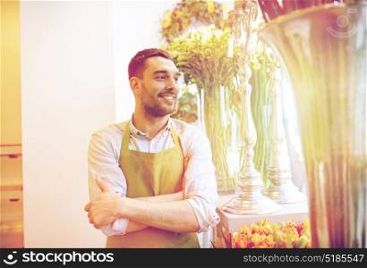 people, sale, retail, business and floristry concept - happy smiling florist man in apron standing at flower shop. happy smiling florist man standing at flower shop
