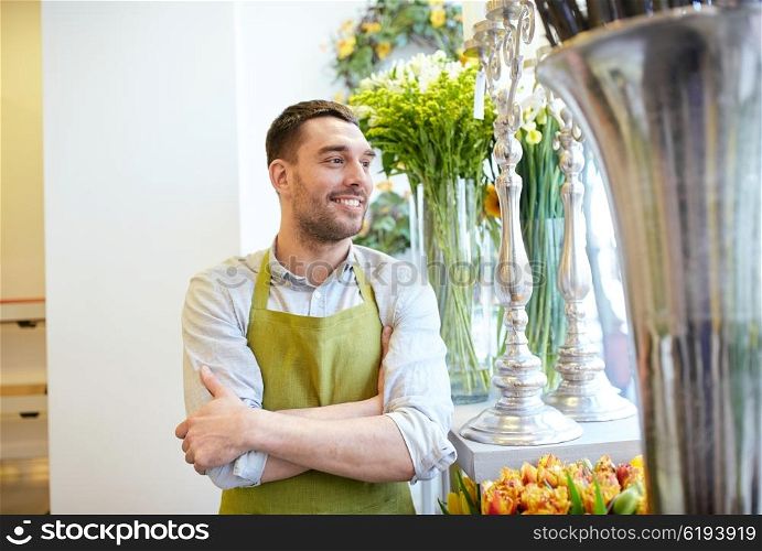 people, sale, retail, business and floristry concept - happy smiling florist man in apron standing at flower shop