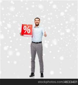 people, sale, shopping, christmas and winter holidays concept - smiling man holding red percentage sign showing thumbs up over snow background