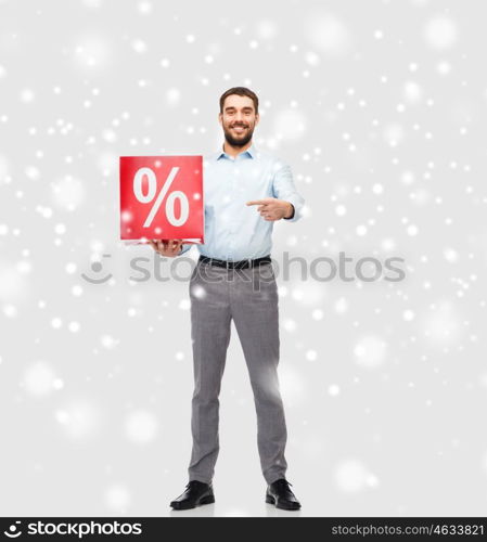 people, sale, shopping, christmas and winter holidays concept - smiling man holding red percentage sign over snow background