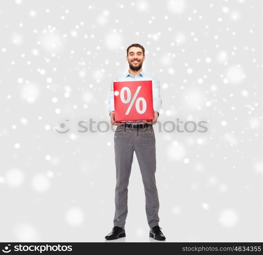 people, sale, shopping, christmas and winter holidays concept - smiling man holding red percentage sign over snow background