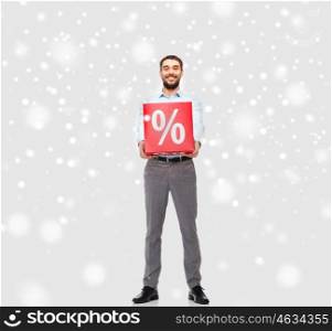 people, sale, shopping, christmas and winter holidays concept - smiling man holding red percentage sign over snow background