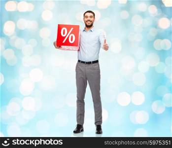 people, sale, shopping, discount and christmas concept - smiling man holding red percentage sign over blue holidays lights background