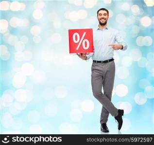 people, sale, shopping, discount and holidays concept - smiling man holding red percentage sign over blue holidays lights background