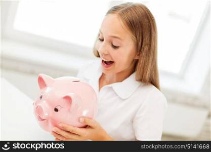 people, saving and finances concept - happy girl with piggy bank at home. happy girl with piggy bank at home