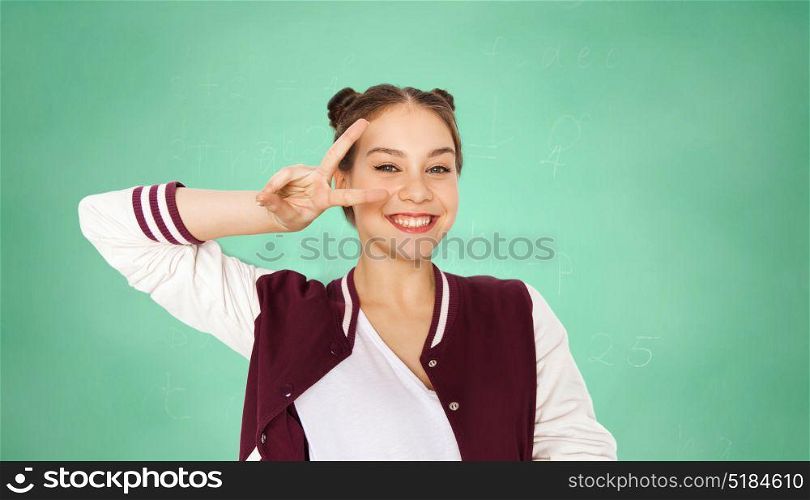 people, school, education and gesture concept - happy smiling pretty teenage student girl showing peace sign over green chalkboard background. happy student girl showing peace sign over green