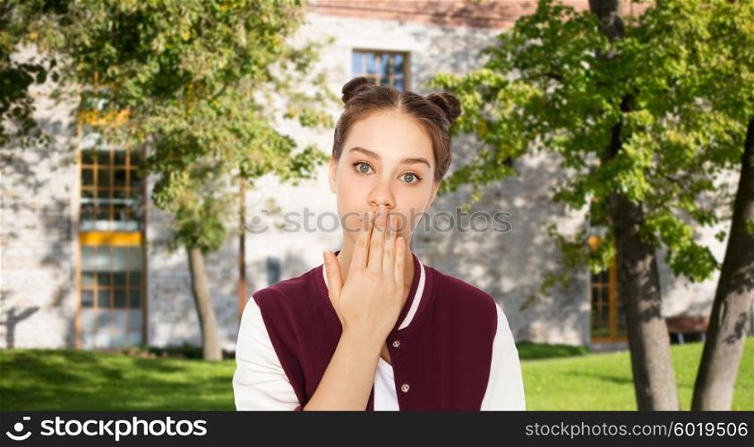 people, school, education, expression and teens concept - confused teenage student girl covering her mouth by hand over summer campus background