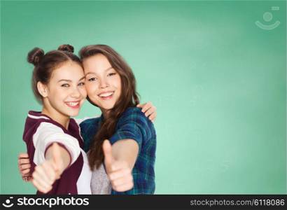 people, school, education, gesture and friends concept - happy smiling pretty teenage student girls hugging and showing thumbs up over green chalk board background