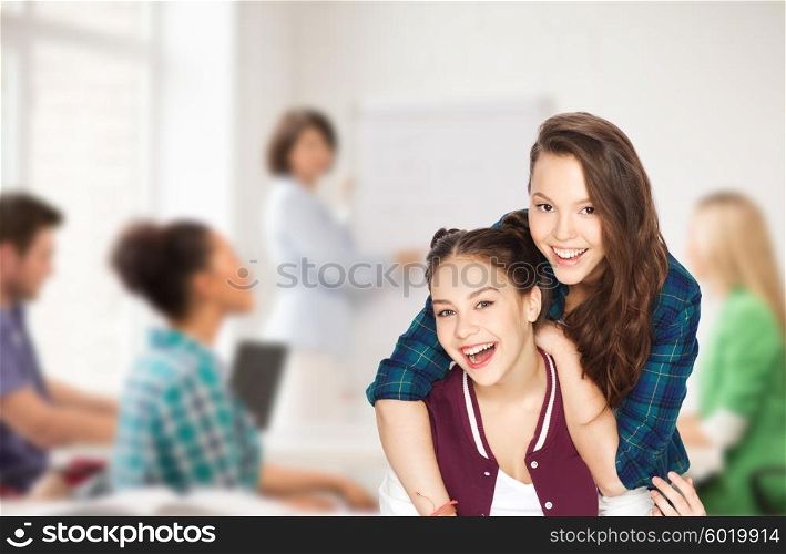 people, school, education, teens and friendship concept - happy smiling pretty teenage student girls having fun over classroom background with teacher and classmates