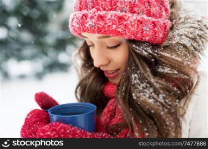 people, season and christmas concept - happy teenage girl or young woman with tea cup outdoors in winter park. happy young woman with tea cup in winter park