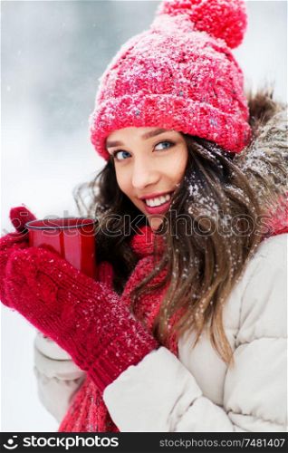 people, season and christmas concept - happy teenage girl or young woman with tea cup outdoors in winter. happy young woman with tea cup in winter park