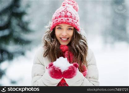 people, season and christmas concept - portrait of happy smiling teenage girl or young woman with snow in winter park. portrait of young woman with snow in winter park