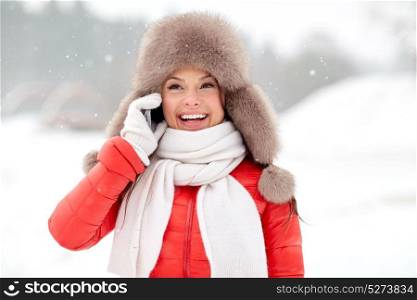 people, season and leisure concept - happy smiling woman in winter fur hat calling on smartphone outdoors. happy woman in winter hat calling on smartphone